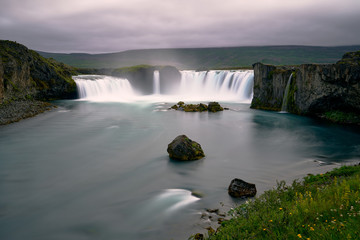 Fototapeta na wymiar spectacular godafoss waterfall in long exposure with green areas and precious rocks