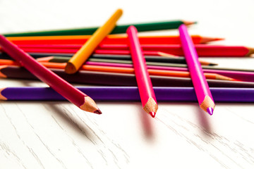Obraz premium many colored sharpened pencils lie on a white wooden table