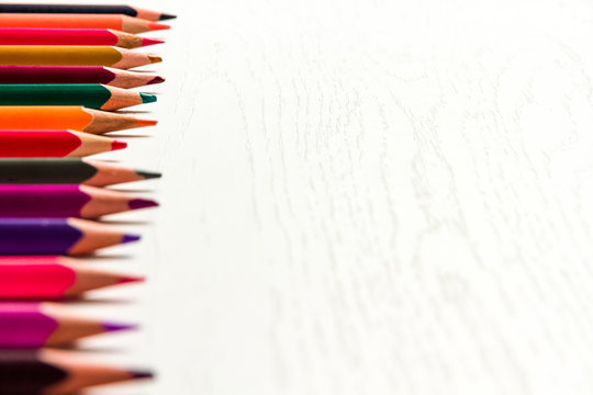 many colored sharpened pencils lie on a white wooden table