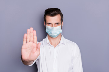 Close-up portrait of his he attractive healthy strict guy medic wearing safety gauze mask showing palm stop sickness illness disease mers cov pandemia isolated over gray color background