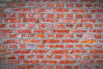 Naklejka premium Renovated old red brick wall texture with vignette. Weathered, grungy red brick wall with peeling old white paint.