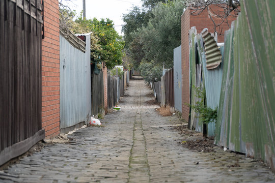 A Coble Stone Alley In Suburban Melbourne With Colapsed Iron Fence