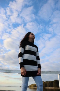Pre teen girl model, wearing striped black and white shirt.  Bright blue skyline in the background