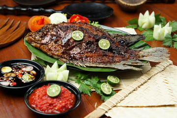 photos of food products, View from above Close up of grilled fish or grilled gouramy with chili sauce and vegetables on a textured wooden table. Usually used for menu list pictures or food pictures in