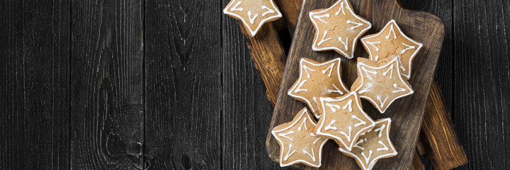 Christmas gingerbread on a wooden Board against the background of fir branches. Gingerbread close-up. Banner	