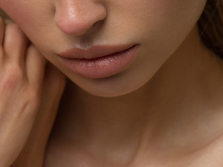 Obraz premium Close-up of woman's lips with fashion natural beige lipstick makeup. Macro sexy pale lipgloss make-up . Gentle pure skin and wavy blonde hair. Cosmetology, Spa, increase in lips