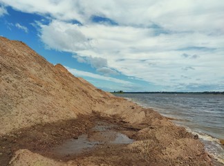 sandy hill by the coastline against the blue cloudy sky