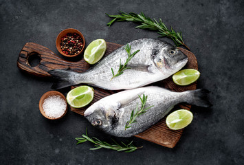 Raw dorado fish with ingredients on stone background