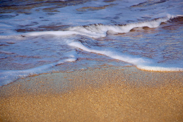 Wave and foam on the sand, background of waves on the sea