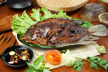 photos of food products, View from above Close up of grilled fish or grilled gouramy with chili sauce and vegetables on a textured wooden table. Usually used for menu list pictures or food pictures in
