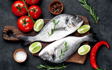 Raw dorado fish with ingredients on stone background