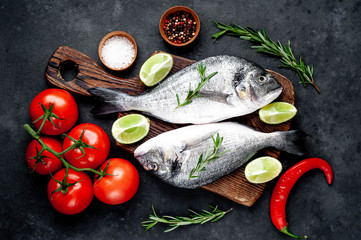 Raw dorado fish with ingredients on stone background