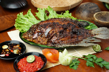 photos of food products, View from above Close up of grilled fish or grilled gouramy with chili sauce and vegetables on a textured wooden table. Usually used for menu list pictures or food pictures in