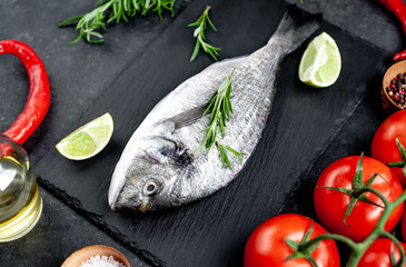 Raw dorado fish with ingredients on stone background