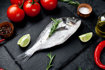 Raw dorado fish with ingredients on stone background