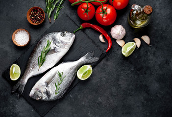 Raw dorado fish with ingredients on stone background with copy space for your text