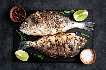 grilled dorado fish with ingredients on stone background