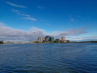 Naklejka premium Beautiful view of high-rise buildings on the riverbank on a sunny day with deep blue sky and light clouds, Parramatta river, Meadowbank, Sydney, New South Wales, Australia 