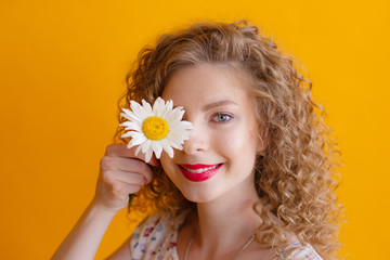 Young woman with makeup, curly hair isolated on yellow background