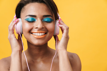 Image of shirtless african american woman smiling and using headphones