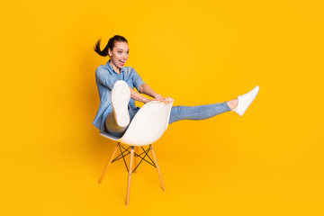 Full size profile side photo of energetic crazy girl sit chair imagine she ride mountain rider fast speed wear good look clothes footwear isolated over vivid color background