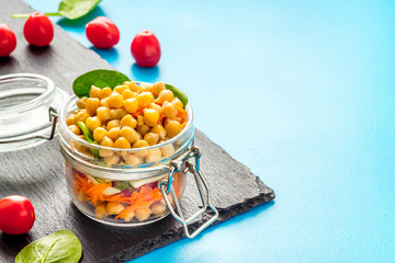 Healthy vegan food. Chickpeas with vegetables in glass jar copy space