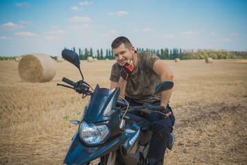 Young man on a motorcycle at field, hobby of modern people, lifestyle 