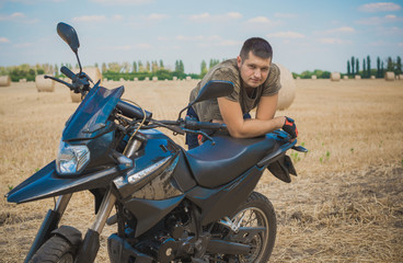 Fototapeta na wymiar Young man on a motorcycle at field, hobby of modern people, lifestyle 
