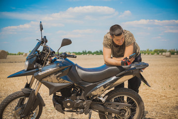Obraz na płótnie Canvas Young man on a motorcycle at field, hobby of modern people, lifestyle 