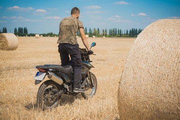 Naklejka na ściany i meble Young man on a motorcycle at field, hobby of modern people, lifestyle 