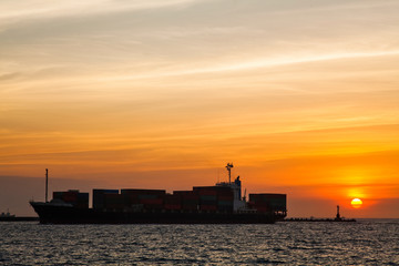Sunset into the sea with the container ship silhouette.