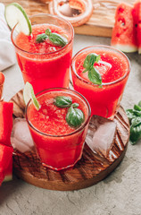 Watermelon lemonade with lime and fresh basil leaves on concrete background. Refreshing summer drink