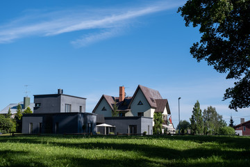 two residential houses on the outskirts of a small town in the middle of summer when everything is surrounded by green grass and green trees