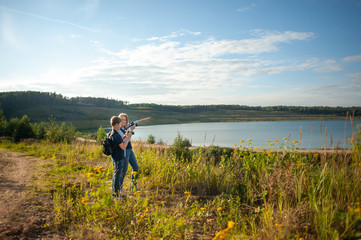 Fototapeta premium Mother and son teenager on a hike with cameras in her hands. The photographer's mother teaches her son to take pictures. The family travels to beautiful natural places.