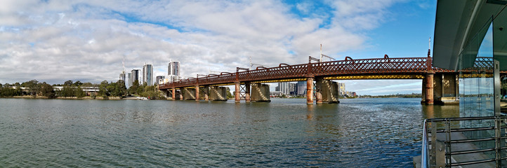 Beautiful panoramic view of a railway bridge across a river on a sunny day with deep blue sky and light clouds, Parramatta river, Meadowbank, Sydney, New South Wales, Australia
