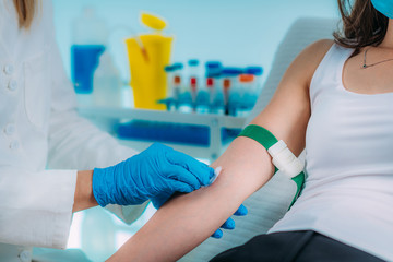 Medical worker with PPE taking blood sample from patient in a hospital