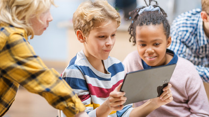 Elementary School Computer Science Class: Children Use Digital Tablet Computers and Smartphones...