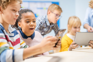 Elementary School Computer Science Class: Children Use Digital Tablet Computers and Smartphones with Augmented Reality Software, They’re Excited, Full of Wonder. Children in STEM, Playing and Learning