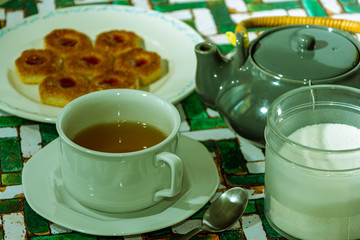 Still life con  Taza de té negro con azúcar, limones y galletas en el fondo de la mesa rústica
