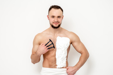Young caucasian man with beard holds razor shaves his chest with white shaving foam on white background. Man shaving his torso