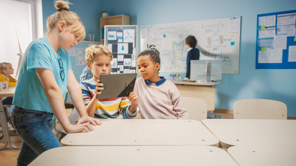 Elementary School Computer Science Class: Two Girls and Boy Use Digital Tablet Computer with Augmented Reality Software, They’re Excited, Full of Wonder, Curiosity. Children in STEM, Playing, Learning