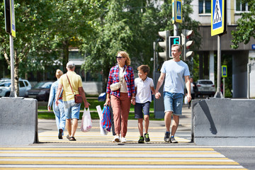 Woman, man and child cross road at crosswalk