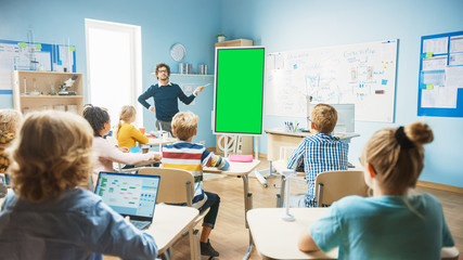 Elementary School Physics Teacher Uses Interactive Digital Whiteboard With Green Screen Mock-up Template. He Leads Lesson to Classroom full of Smart Diverse Children. Science Class with Kids Listening