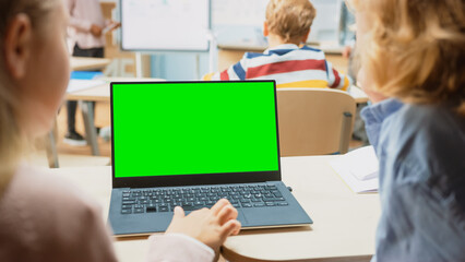 Elementary School Science Class: Over the Shoulder Little Boy and Girl Use Laptop with Green Screen...
