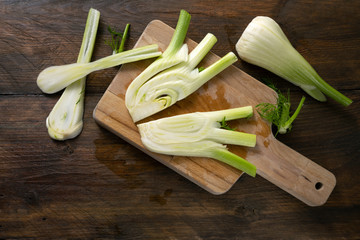 Sliced raw fennel on a cutting board and a dark rustic wooden table, healthy vegetable, copy space, flat lay, view from above