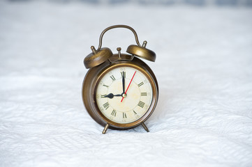 Retro clock stands on the bedspread in the bedroom. Time to get up