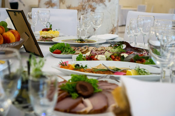 beautiful table setting in light colors with dishes and assorted food on a table with a white tablecloth for a party, wedding or other special event. Restaurant business and service industry concept.
