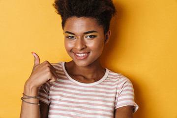 Image of african american woman showing thumb up gesture and smiling