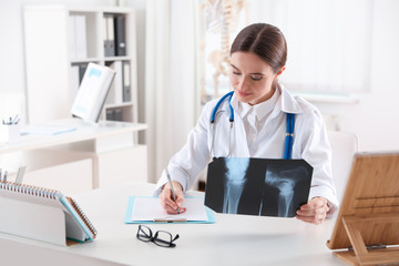 Orthopedist examining X-ray picture at desk in clinic