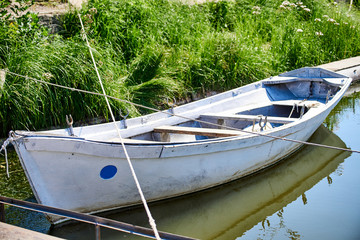 Obraz premium An old boat stands at the bank of the Kutum River overgrown with green grass